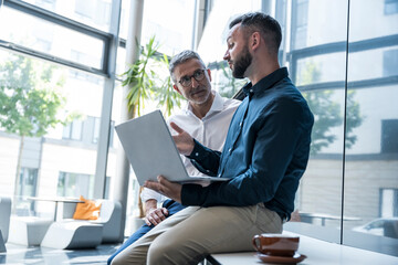 Manager consulting colleague with tablet in modern office