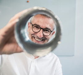 Engineer smiling through pipe in modern office setting