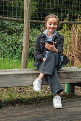 Reading a funny message on her smartphone while sitting on a park bench