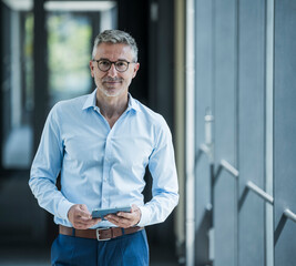 Professional portrait of businessman holding tablet in modern office