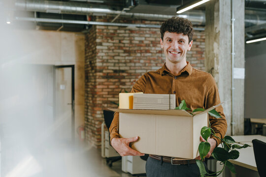 Smiling businessperson arriving at office with box on first day