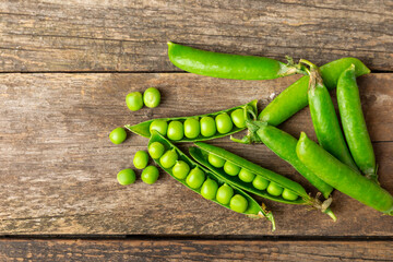 Fresh green pea pods with green peas on a wooden background. Sweet green peas. Green pea beans...