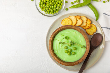 Green pea soup on a wooden table. Fresh pea soup bowl. Delicious healthy cream soup in a bowl with green peas and croutons. Healthy vegan puree. Copy space. Space for text.
