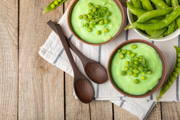 Green pea soup on a wooden table. Fresh pea soup bowl. Delicious healthy cream soup in a bowl with green peas and croutons. Healthy vegan puree. Copy space. Space for text.