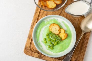 Green pea soup on a wooden table. Fresh pea soup bowl. Delicious healthy cream soup in a bowl with green peas and croutons. Healthy vegan puree. Copy space. Space for text.