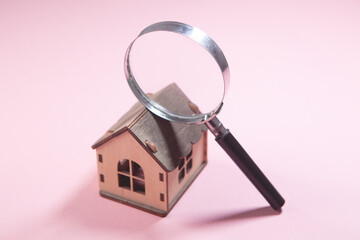 magnifier and house on pink background. real estate concept