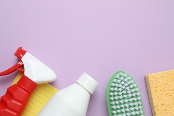 Household cleaning supplies including brush, sponges, and bottle arranged as a frame on a color...
