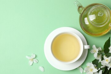 Green tea with jasmine in cup and teapot on pastel background