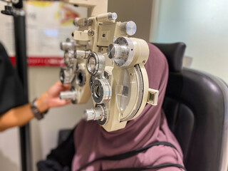 unrecognizable eye doctor examining young muslim women eyes while using autorefractor in clinic