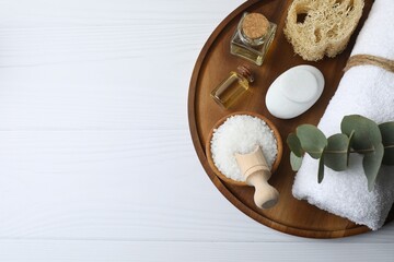 Spa products, aromatherapy, atmosphere of relax. Spa essentials on wooden tray in bathroom, essential oil, bath salt, towel, sea stone, eucalyptus branches