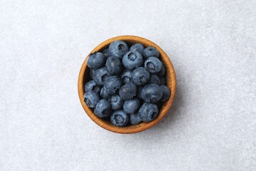 Top view of bowl with fresh tasty blueberries on gray table, close up