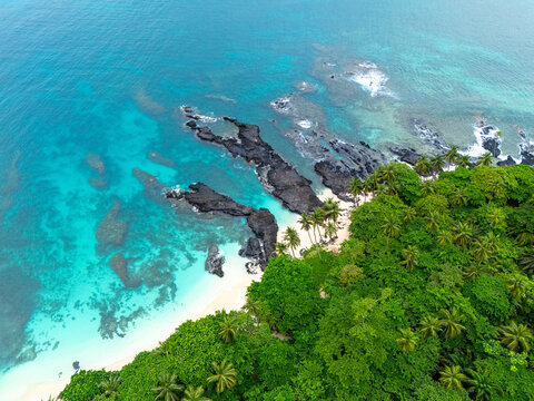 Tropical  Rolas Island on S&atilde;o Tom&eacute; aerial view with black volcanic rocks, white sand, turquoise water and lush green palm forest.
