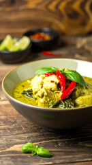 Thai Green Curry: An enticing shot of Thai green curry, aromatic basil leaves and fiery red chili peppers arranged in a deep bowl, exuding authentic culinary vibes and creating a sensory delight.