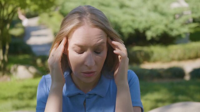 Girl suffering from magnetic storm symptoms headache weather sensitivity rubbing temples health issue fatigue pressure change meteoropathy neurology pain stress disorder outdoors