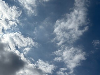 Bright blue sky with a smooth spread of white clouds, sunlight is seen spreading softly from behind...