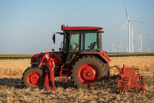 Farmer with tractor and wind turbine in field representing sustainable farming