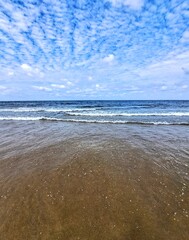 waves on the beach. Background of beach landscape, North Sea coast in The Hague in summer in sunny weather. And blue sky with white clouds.