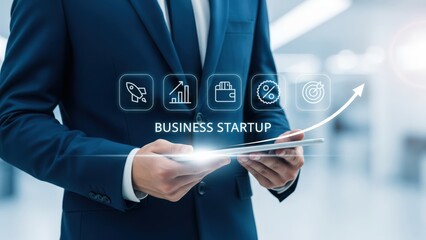 Obraz premium Man in blue suit holding tablet with glowing icons of business startup and arrow rising upward to show progress and success in startup