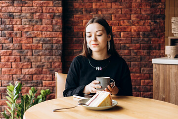 Young woman drinking black filter coffee with cake in morning cafe scene.
