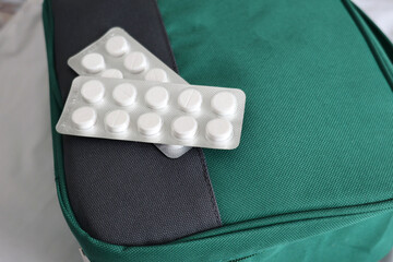 white round tablets in blister packs placed on a green first aid kit bag