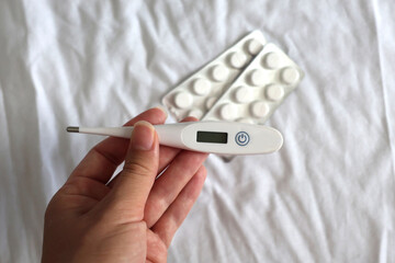 Digital thermometer and two blister packs of white tablets