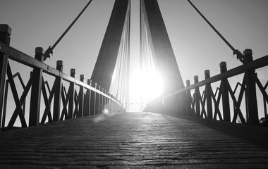 Architectural silhouette of suspension bridge reaching to luminous sunlit