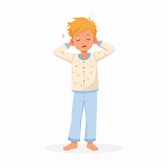 Fototapeta premium A young boy in pajamas stretches after waking up, looking sleepy.