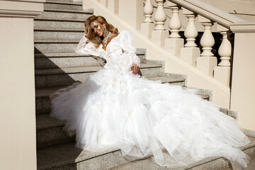 Stunning bride in luxurious white wedding gown with dramatic tulle train posing gracefully on...
