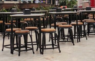 Mesa y taburetes de madera en terraza en una cafetería del centro comercial Islazul en Madrid, España