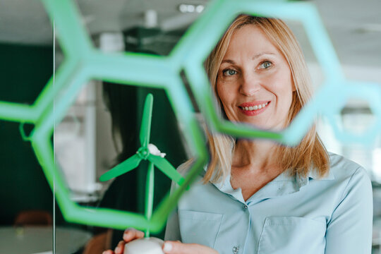 Smiling professional with wind generator model representing green technology