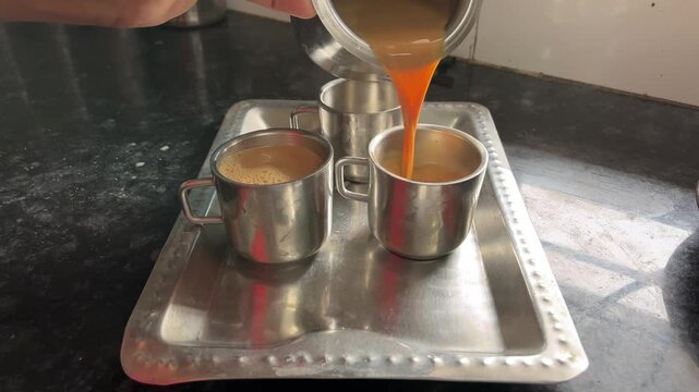 Close-up video of pouring hot tea into three cups placed on a tray, perfect for concepts of hospitality, beverage preparation, and traditional tea serving.