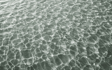 Dancing shadows and lights of glittering water surface in the pool