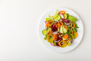Cucumber salad on a wooden background.Homemade salad with fresh vegetables, cucumber, tomato, sweet pepper and lettuce in a plate.Vegetarian spring salad.Vegetarian diet.Healthy eating.Space for text