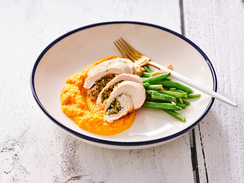 Enjoy a flavorful plate featuring garlic and herb stuffed chicken, paired with creamy sweet potato mash and fresh green beans, perfect for a hearty dinner