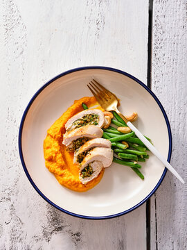 Savor the flavors of garlic and herb stuffed chicken accompanied by creamy sweet potato mash and crisp green beans, perfect for a wholesome meal any time of the day