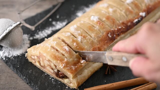 Cutting homemade apple strudel on rustic table