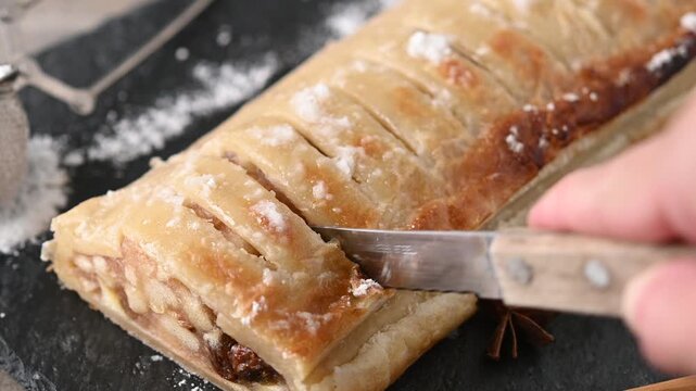Cutting homemade apple strudel on rustic table