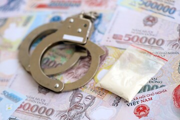 Vietnamese dong currency money bills and cocaine pack with handcuffs. The concept of drug crimes
