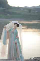 Young woman in traditional clothing by the water.