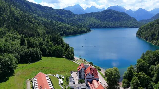 Turquoise Alpsee Lake in Bavaria Germany surrounded by lush green forest and mountain peaks under a bright summer sky