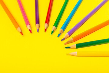 Colored pencils on a bright colored background. Equipment for coloring. Stationery for...