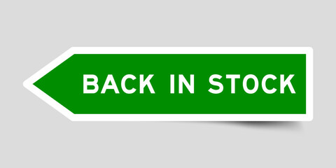 Green color arrow shape sticker label with word back in stock on gray background
