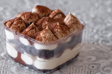 Tiramisu cake in a glass cup. Tiramisu slice, layers of cream and soaked sponge, dusted with cocoa
