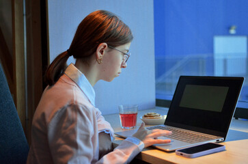 Focused female entrepreneur working remotely on laptop in modern office