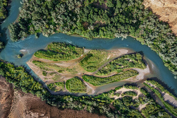 Aerial view of a river flowing through a green landscape, creating small islands and a beautiful...
