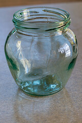 A glass transparent jar stands on tabletop and a blurred background. Blank for art works on theme...