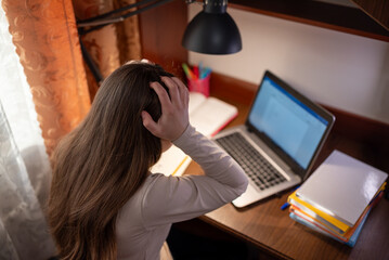 Student in despair over an incomprehensible task on her laptop. A girl sits at a desk with a...