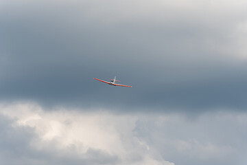 Front view of airplane flying in cloudy dramatic sky background