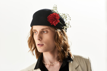 Handsome young man showcases feminine style with trendy hat and unique floral accent