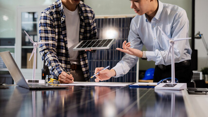 Engineering Team working with blueprints for sketching a construction project, green energy and solar panel concept. © NINENII